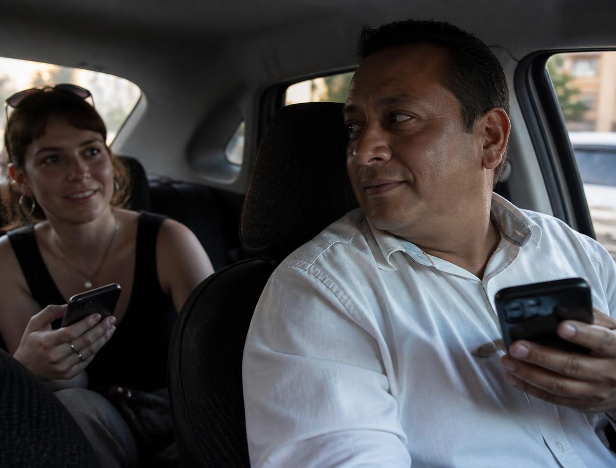 Un chauffeur de taxi et sa passagère communiquent chacun sur son propre téléphone